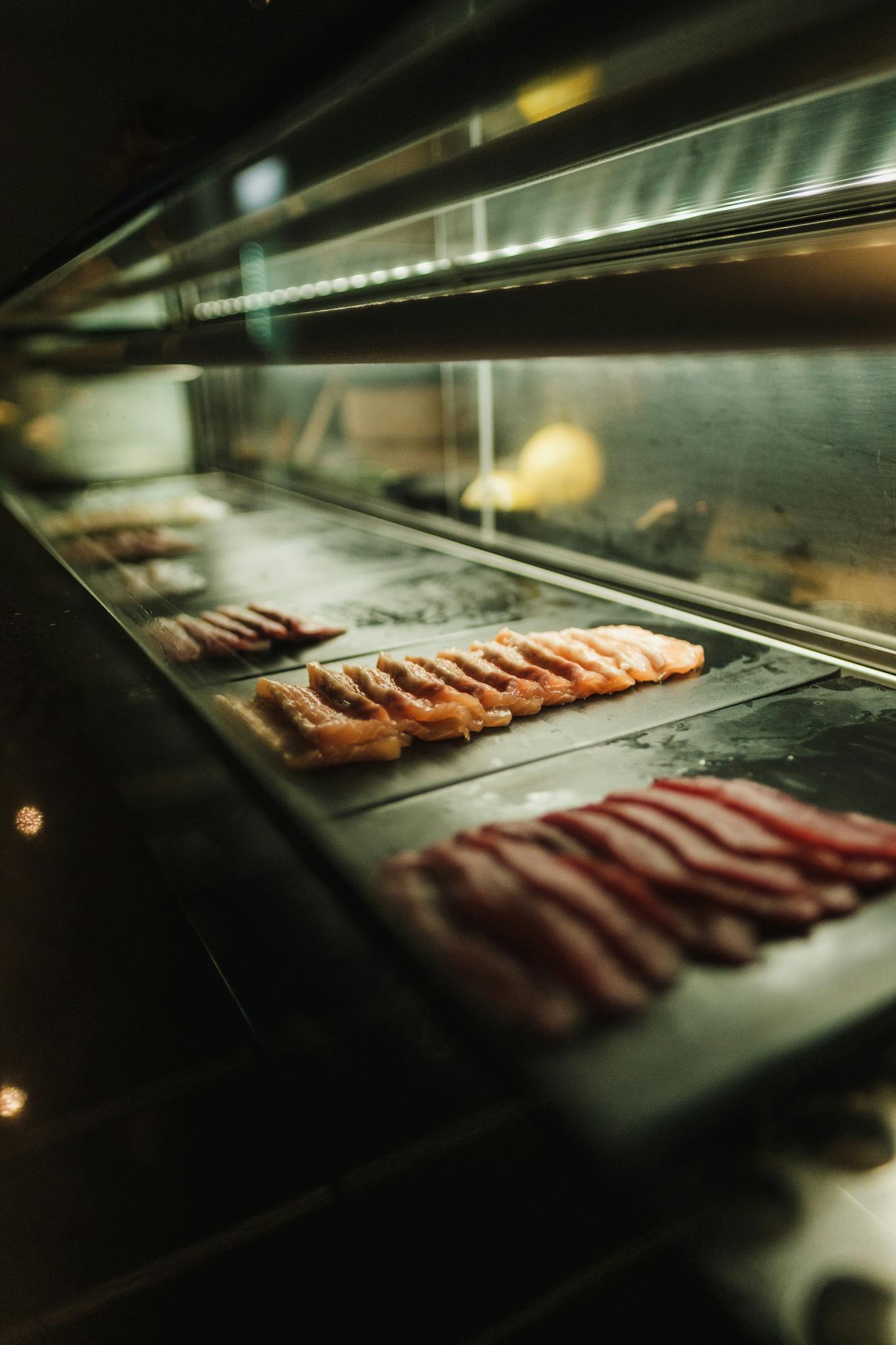 Slices of raw meat displayed in a well-lit refrigerated case, showcasing a premium selection.